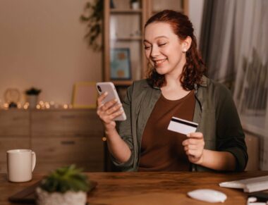 mulher-sorridente-usando-smartphone-em-casa-com-cartao-de-credito_1